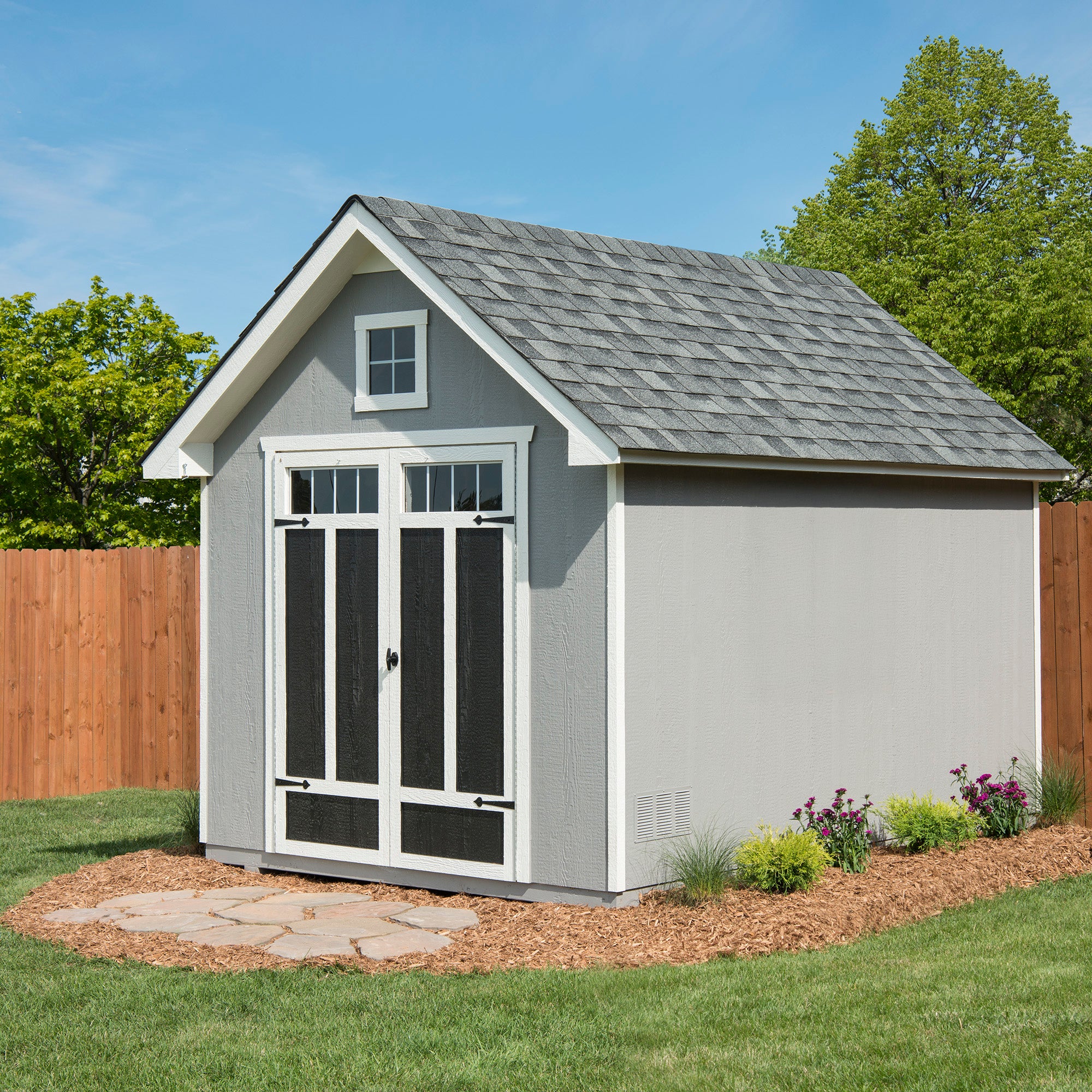 Storage shed with decorative double doors, a dormer window, and a landscaped yard. Storage shed with decorative double doors, a dormer window, and a landscaped yard.
