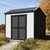 storage shed with a metal roof, double doors, and a gravel path leading to it.