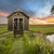 Storage shed in middle of the field with fence in front 